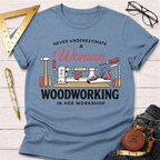 Women's funny woodworking graphic tee shirt for female woodworkers, makers, and DIY builders — Sawdust & Ponytails. Light blue cotton tee with "Never Underestimate A Woman Woodworking In Her Workshop" text and tools graphic.