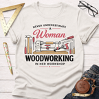 Women's funny woodworking graphic tee shirt for female woodworkers, makers, and DIY builders — Sawdust & Ponytails. White cotton tee with "Never Underestimate A Woman Woodworking In Her Workshop" text and tool graphics.