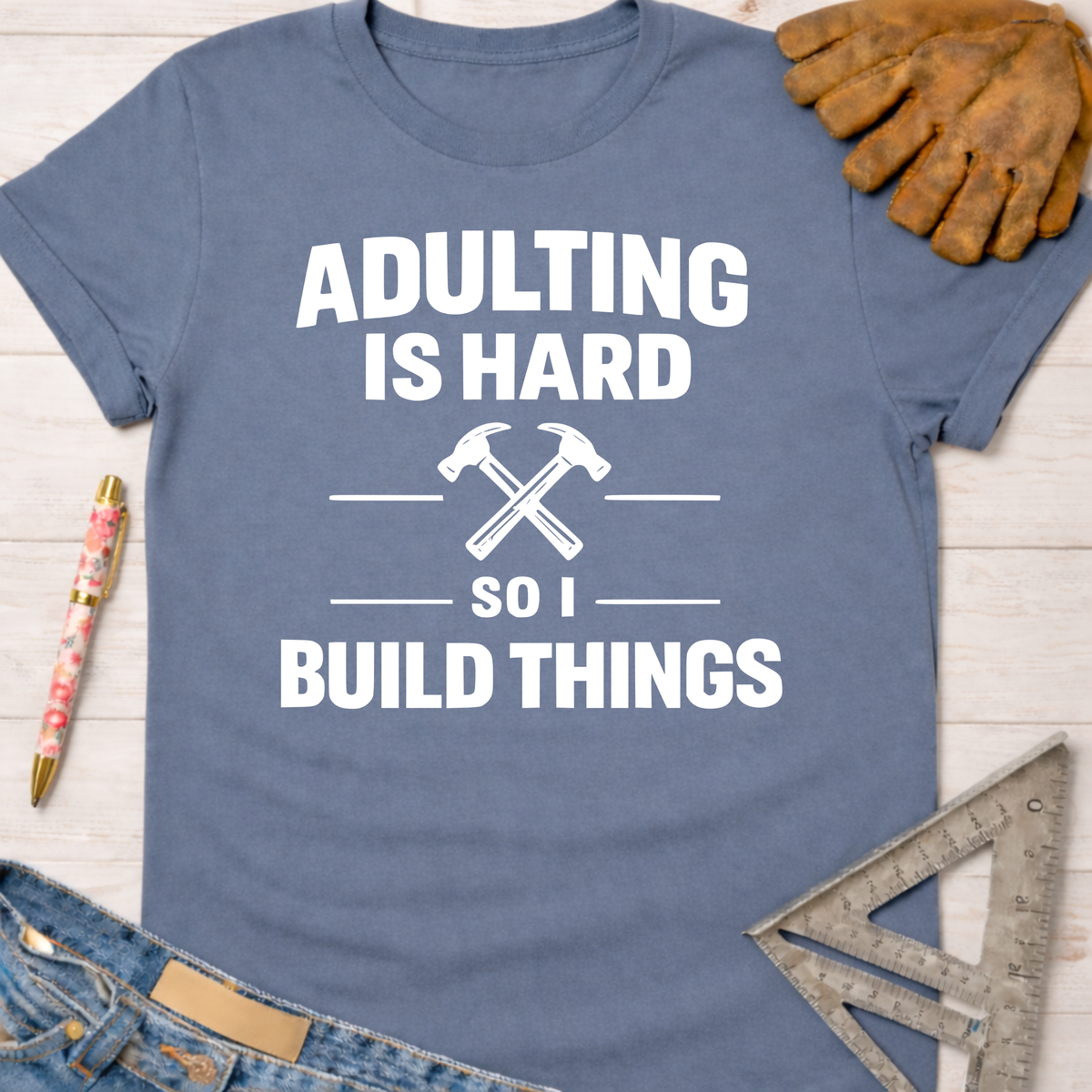 Women's funny woodworking graphic tee shirt for female woodworkers, makers, and DIY builders — Sawdust & Ponytails. Blue cotton tee with "Adulting Is Hard So I Build Things" text and crossed hammers.