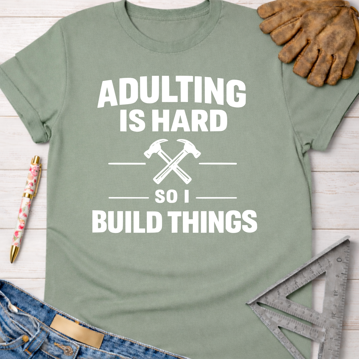Sage green "Adulting Is Hard So I Build Things" tee with crossed hammers, for female woodworkers.