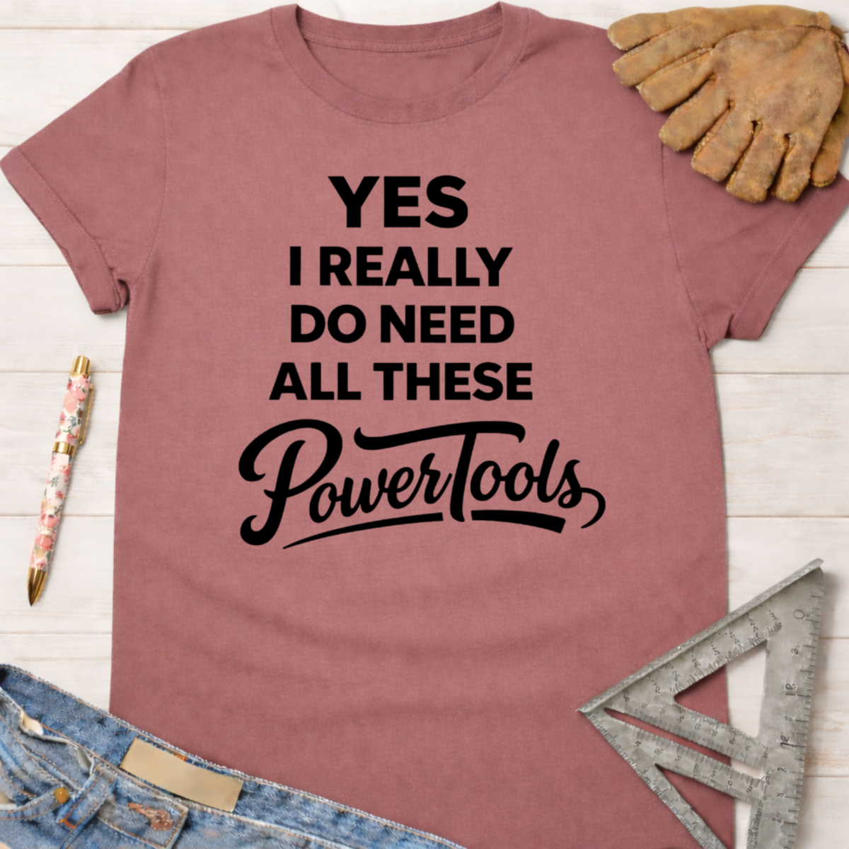 Women's funny woodworking graphic tee shirt for female woodworkers, makers, and DIY builders — Sawdust & Ponytails. Mauve t-shirt with "YES I REALLY DO NEED ALL THESE PowerTools" in black text.