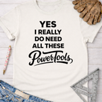 Women's funny woodworking graphic tee shirt for female woodworkers, makers, and DIY builders — Sawdust & Ponytails. White cotton tee with "YES I REALLY DO NEED ALL THESE PowerTools" in black text.