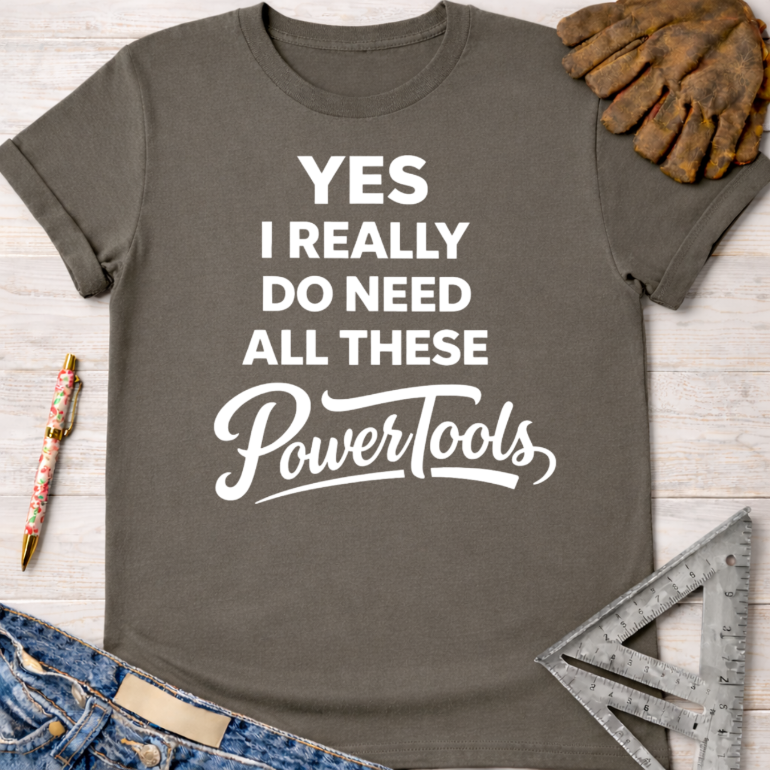 Women's funny woodworking graphic tee shirt for female woodworkers, makers, and DIY builders — Sawdust & Ponytails. Dark gray cotton tee with "YES I REALLY DO NEED ALL THESE PowerTools" in white text.