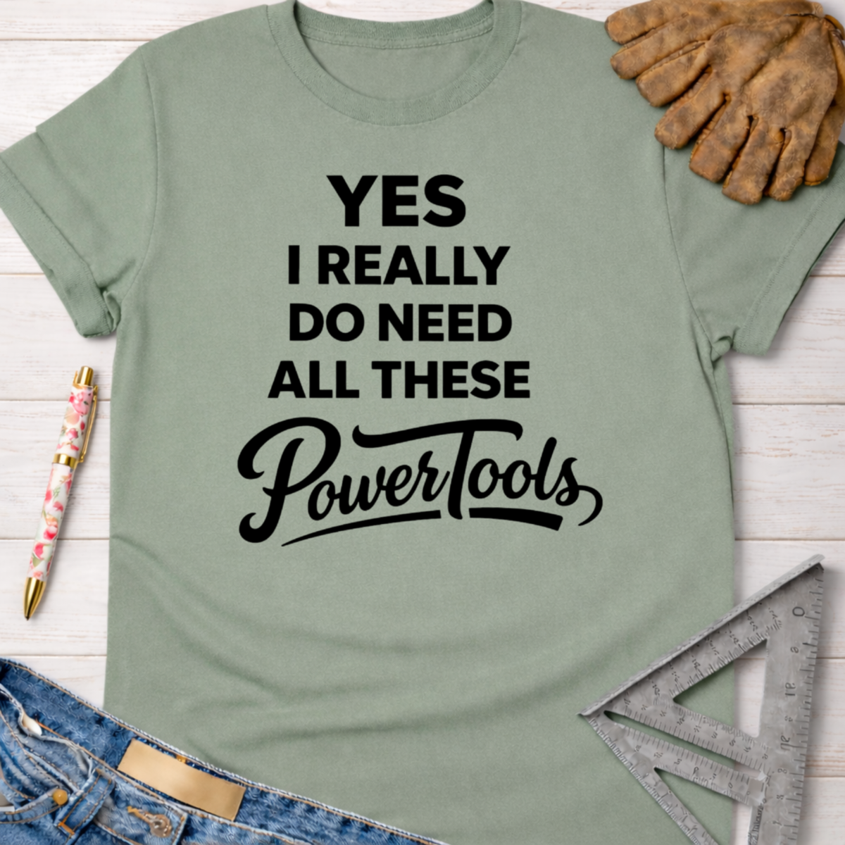 Women's funny woodworking graphic tee shirt for female woodworkers, makers, and DIY builders — Sawdust & Ponytails. Sage green cotton tee with "YES I REALLY DO NEED ALL THESE PowerTools" in black text.