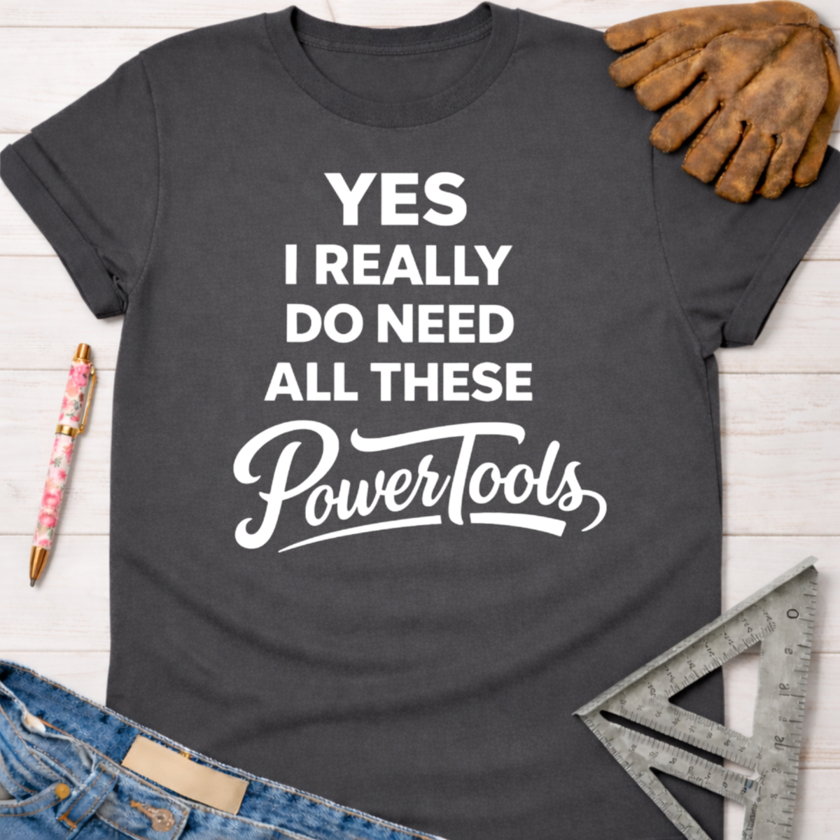Women's funny woodworking graphic tee shirt for female woodworkers, makers, and DIY builders — Sawdust & Ponytails. Dark gray short-sleeve t-shirt with white text: "YES I REALLY DO NEED ALL THESE PowerTools".