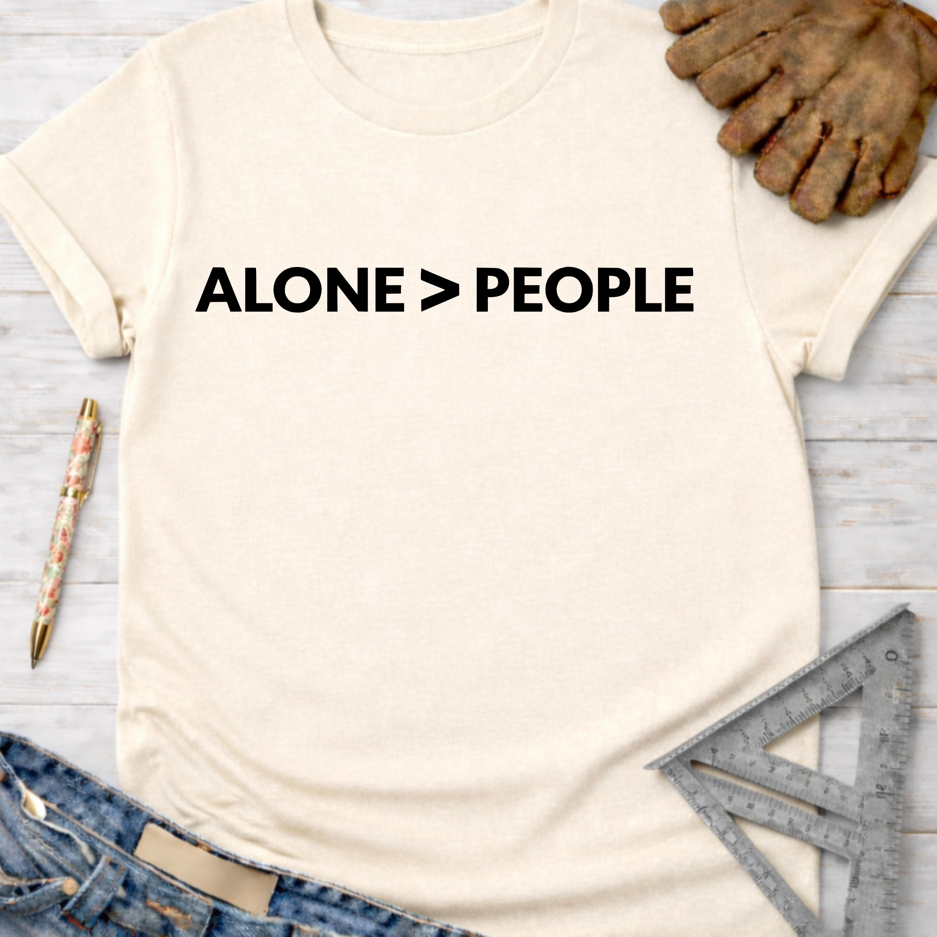 Women's funny woodworking graphic tee shirt for female woodworkers, makers, and DIY builders — Sawdust & Ponytails. Cream t-shirt with "ALONE > PEOPLE" in black text.