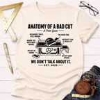 Women's funny woodworking graphic tee shirt for female woodworkers, makers, and DIY builders — Sawdust & Ponytails. Cream t-shirt with "Anatomy of a Bad Cut" graphic.