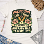 Women's funny woodworking graphic tee shirt for female woodworkers, makers, and DIY builders — Sawdust & Ponytails. White cotton tee with "Making Shit Because Therapy Has A Waitlist" graphic featuring hammers and flowers.