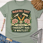 Women's funny woodworking graphic tee shirt for female woodworkers, makers, and DIY builders — Sawdust & Ponytails. Sage green cotton tee with "Making Shit Because Therapy Has A Waitlist" graphic, hammers, and flowers.