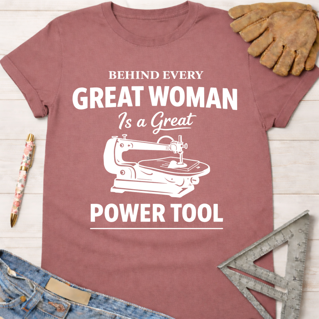 Women's funny woodworking graphic tee shirt for female woodworkers, makers, and DIY builders — Sawdust & Ponytails. Mauve cotton tee with "Behind Every Great Woman Is a Great Power Tool" text and scroll saw graphic.