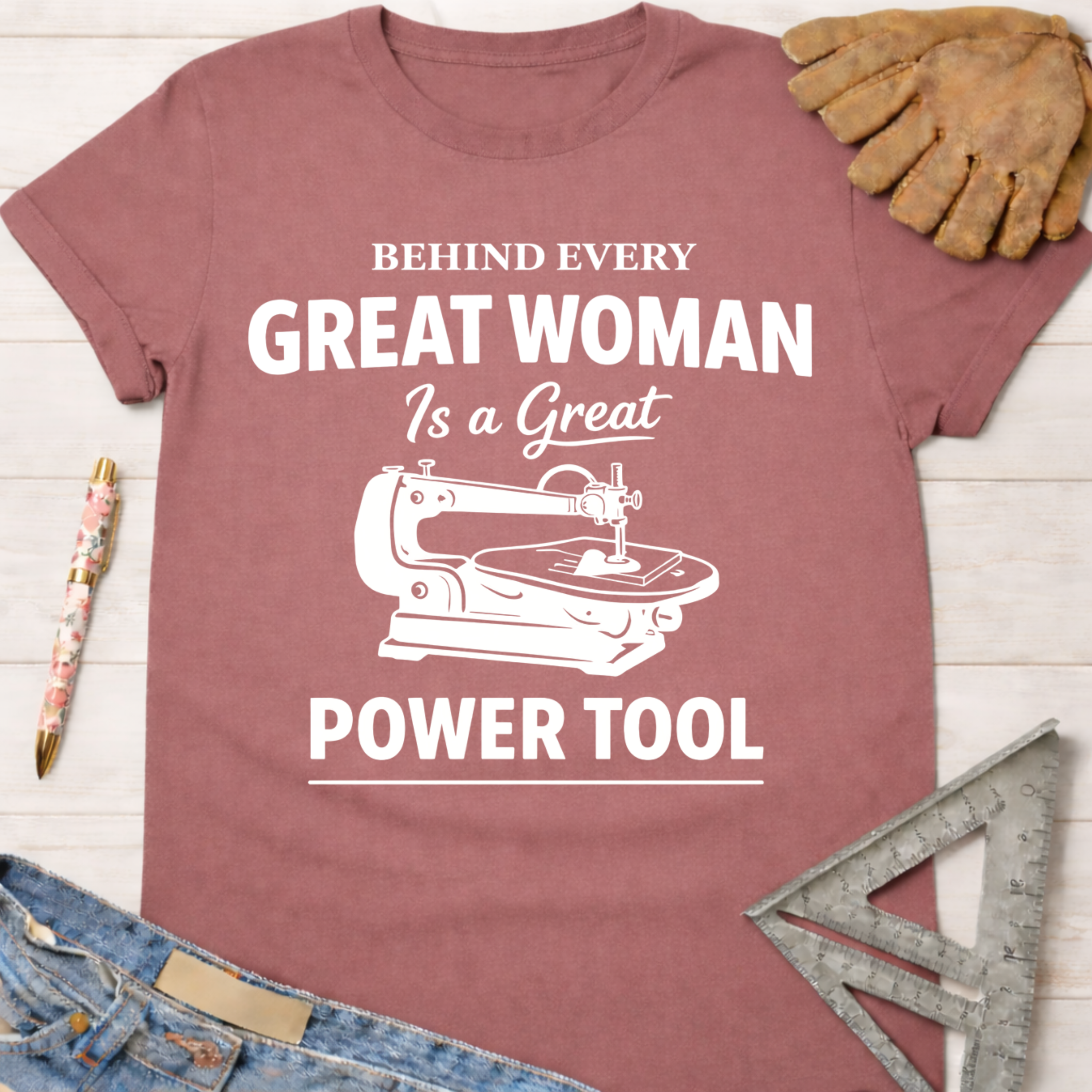 Women's funny woodworking graphic tee shirt for female woodworkers, makers, and DIY builders — Sawdust & Ponytails. Mauve cotton tee with "Behind Every Great Woman Is a Great Power Tool" text and scroll saw graphic.