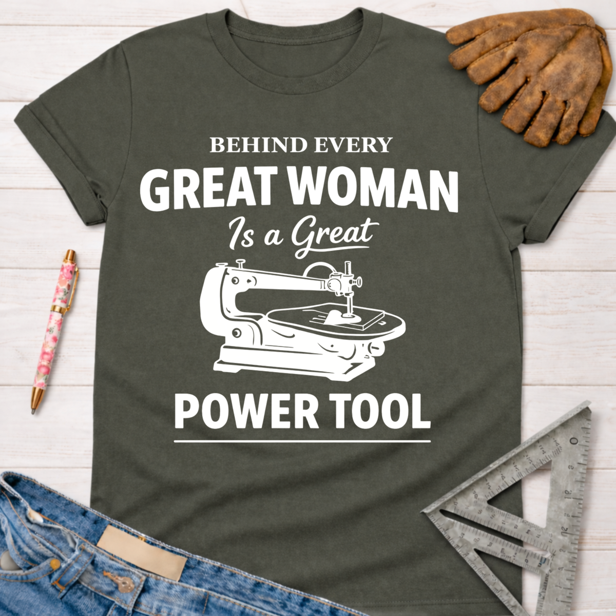 Women's funny woodworking graphic tee shirt for female woodworkers, makers, and DIY builders — Sawdust & Ponytails. Dark gray cotton tee with "Behind Every Great Woman Is a Great Power Tool" text and a sewing machine graphic.