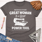 Charcoal gray cotton tee with "Behind Every Great Woman Is a Great Power Tool" text and scroll saw graphic. Women's funny woodworking graphic tee shirt for female woodworkers, makers, and DIY builders — Sawdust & Ponytails.