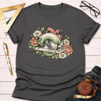 Dark gray Bloom & Blade T-shirt with a floral circular saw graphic, on a white wood background.