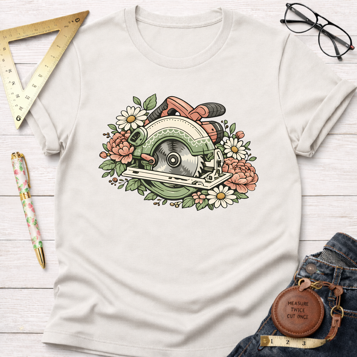 Off-white Bloom & Blade T-shirt with a floral circular saw graphic, surrounded by daisies and pink flowers.