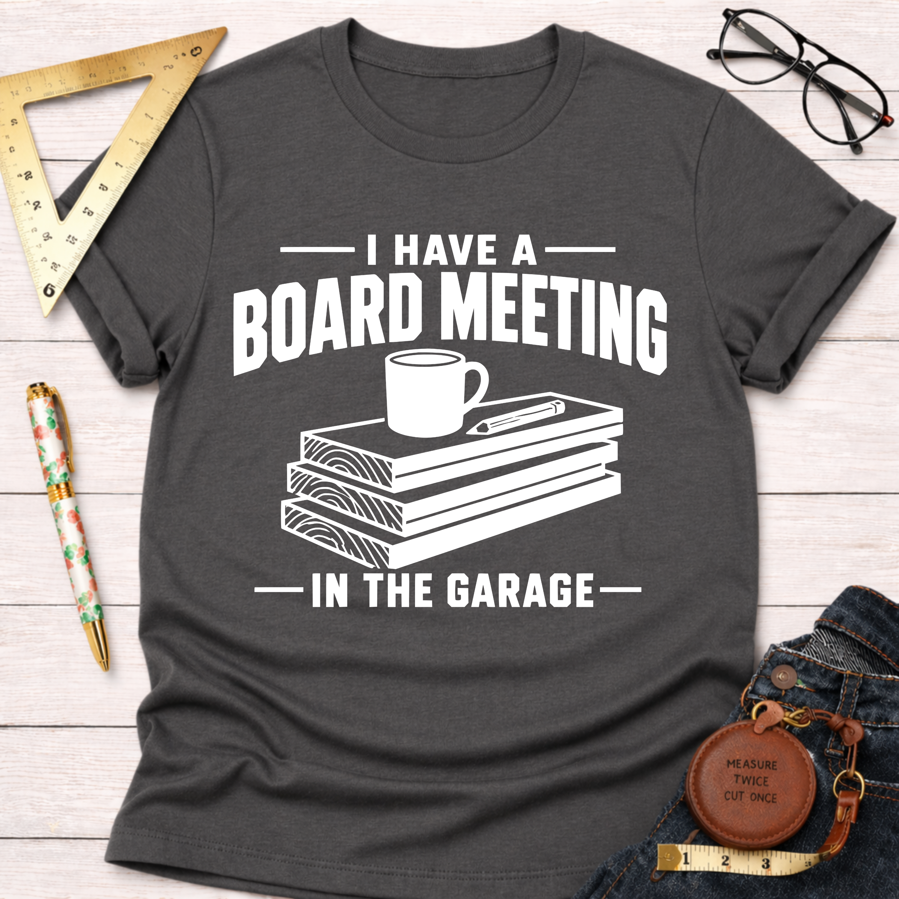 Charcoal gray heather t-shirt with "I Have A Board Meeting In The Garage" text and wood stack graphic.