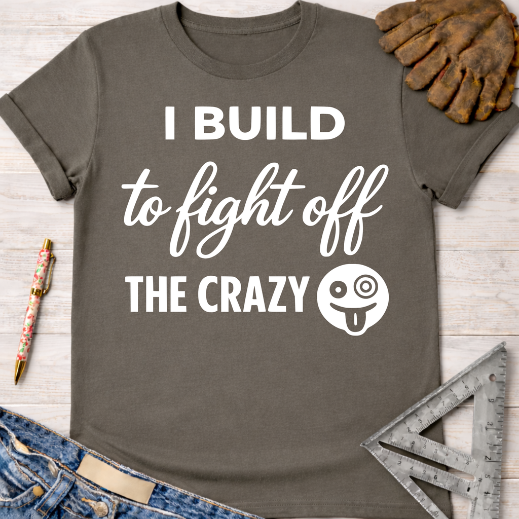 Women's funny woodworking graphic tee shirt for female woodworkers, makers, and DIY builders — Sawdust & Ponytails. Dark gray cotton t-shirt with "I BUILD to fight off THE CRAZY" in white text and a silly face emoji.