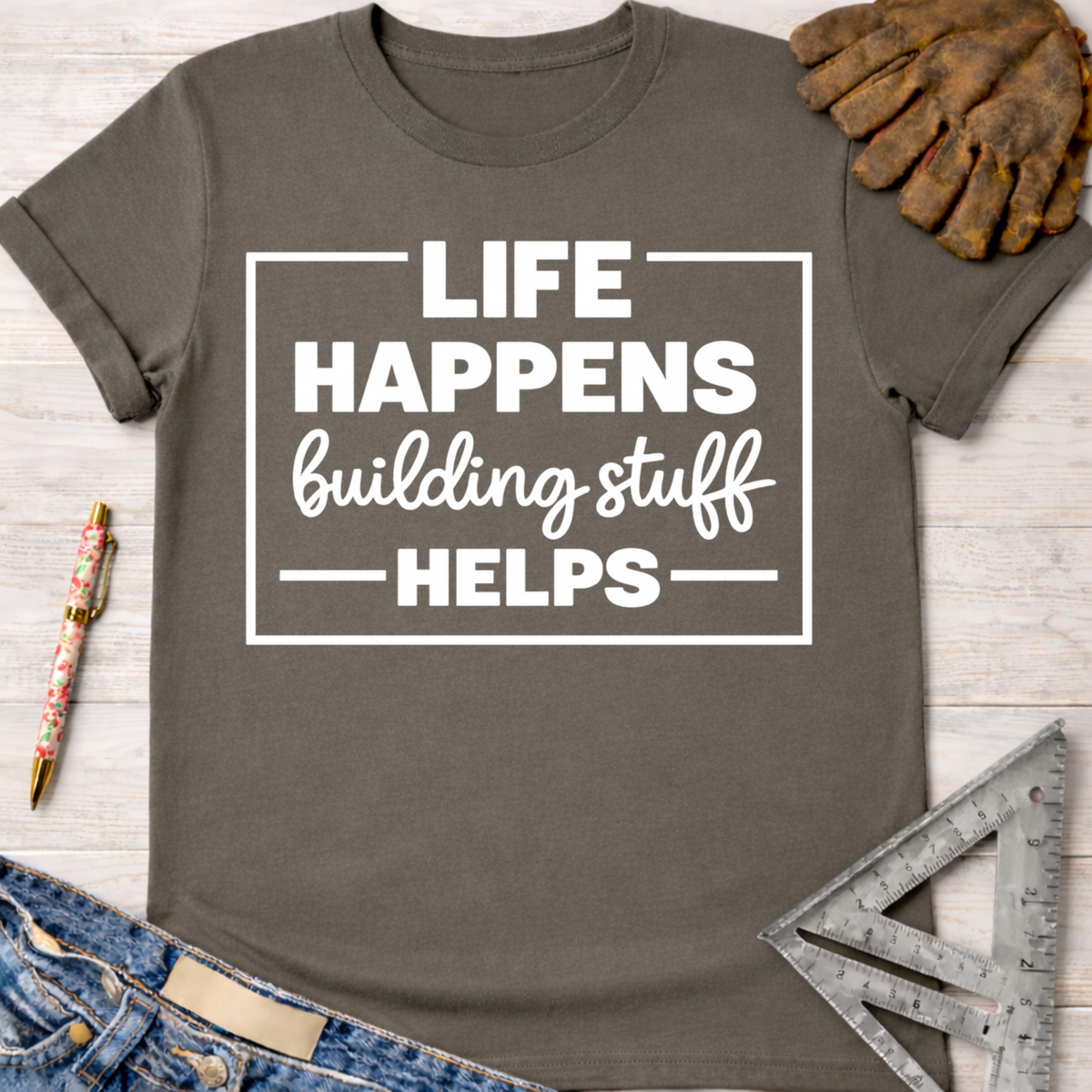 Women's funny woodworking graphic tee shirt for female woodworkers, makers, and DIY builders — Sawdust & Ponytails. Dark gray cotton tee with "Life Happens Building Stuff Helps" in white text.