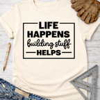 Women's funny woodworking graphic tee shirt for female woodworkers, makers, and DIY builders — Sawdust & Ponytails. Cream short-sleeve tee with "Life Happens Building Stuff Helps" graphic.