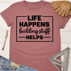 Women's funny woodworking graphic tee shirt for female woodworkers, makers, and DIY builders — Sawdust & Ponytails. Mauve short-sleeve tee with "Life Happens Building Stuff Helps" text.