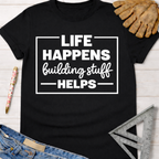 Women's funny woodworking graphic tee shirt for female woodworkers, makers, and DIY builders — Sawdust & Ponytails. Black cotton tee with "Life Happens Building Stuff Helps" in white text.