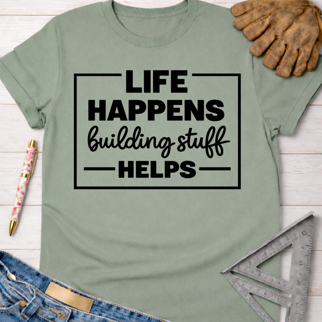 Women's funny woodworking graphic tee shirt for female woodworkers, makers, and DIY builders — Sawdust & Ponytails. Sage green cotton tee with "Life Happens Building Stuff Helps" text.