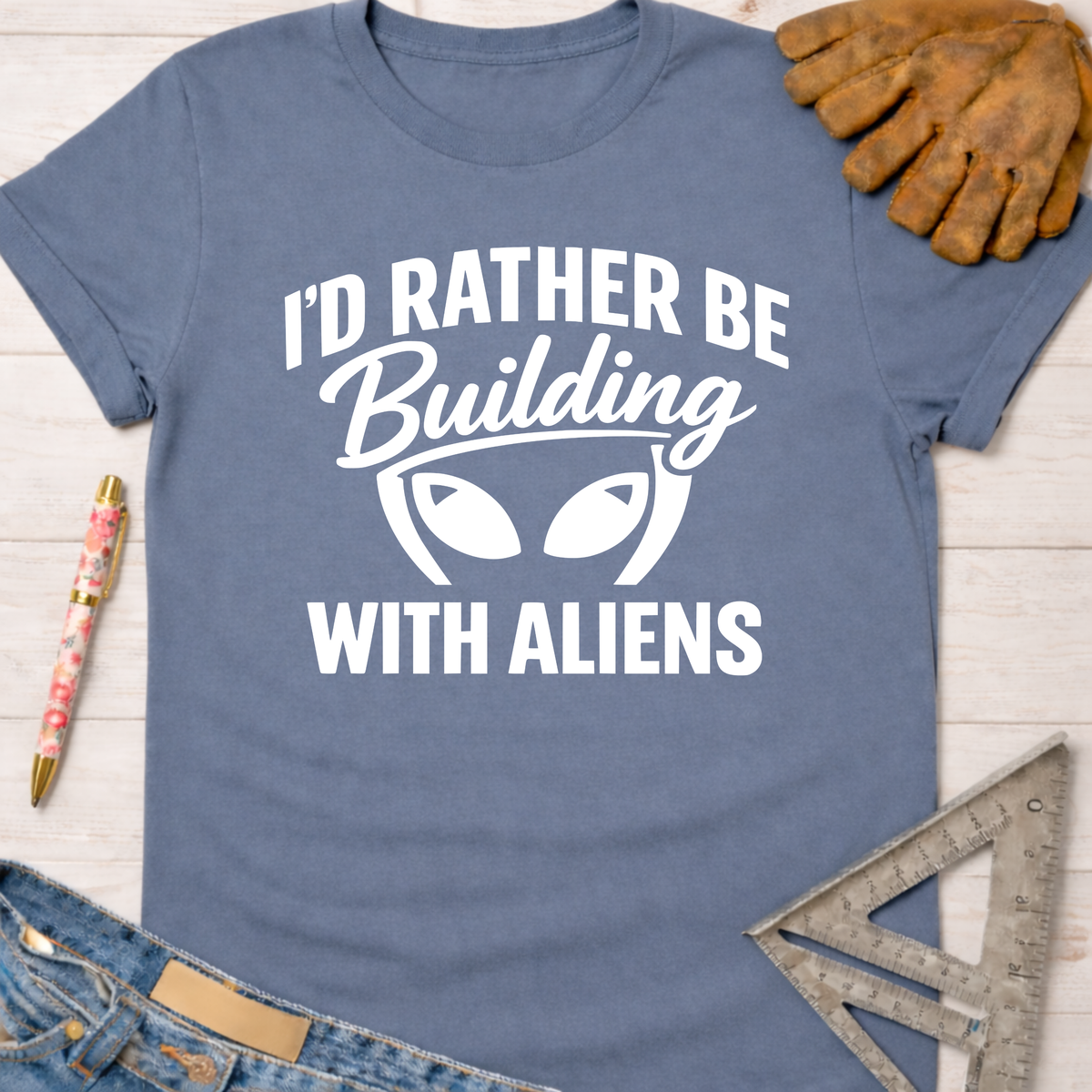 Women's funny woodworking graphic tee shirt for female woodworkers, makers, and DIY builders — Sawdust & Ponytails. Blue t-shirt with "I'd Rather Be Building With Aliens" graphic.