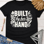 Black cotton tee with "Built by her HAND" graphic, floral and tool accents. Women's funny woodworking graphic tee shirt for female woodworkers, makers, and DIY builders — Sawdust & Ponytails.