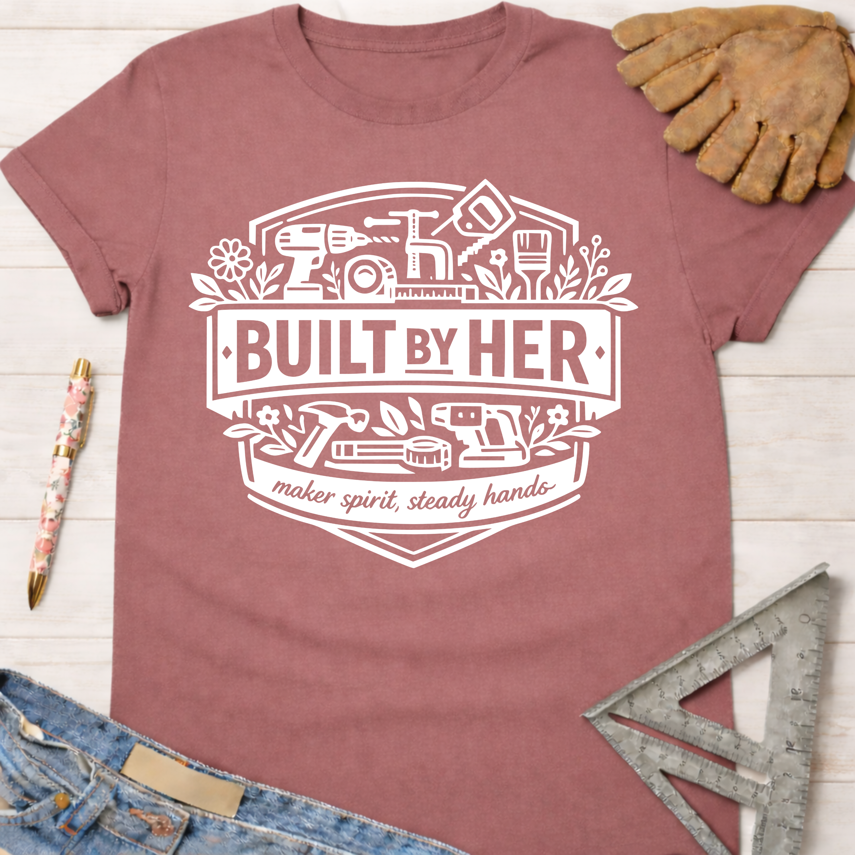 Women's funny woodworking graphic tee shirt for female woodworkers, makers, and DIY builders — Sawdust & Ponytails. Mauve cotton tee with "Built By Her" tools graphic.