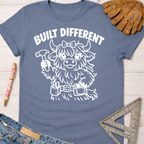 Women's funny woodworking graphic tee shirt for female woodworkers, makers, and DIY builders — Sawdust & Ponytails. Blue tee with "Built Different" and a cute Highland cow holding a hammer.