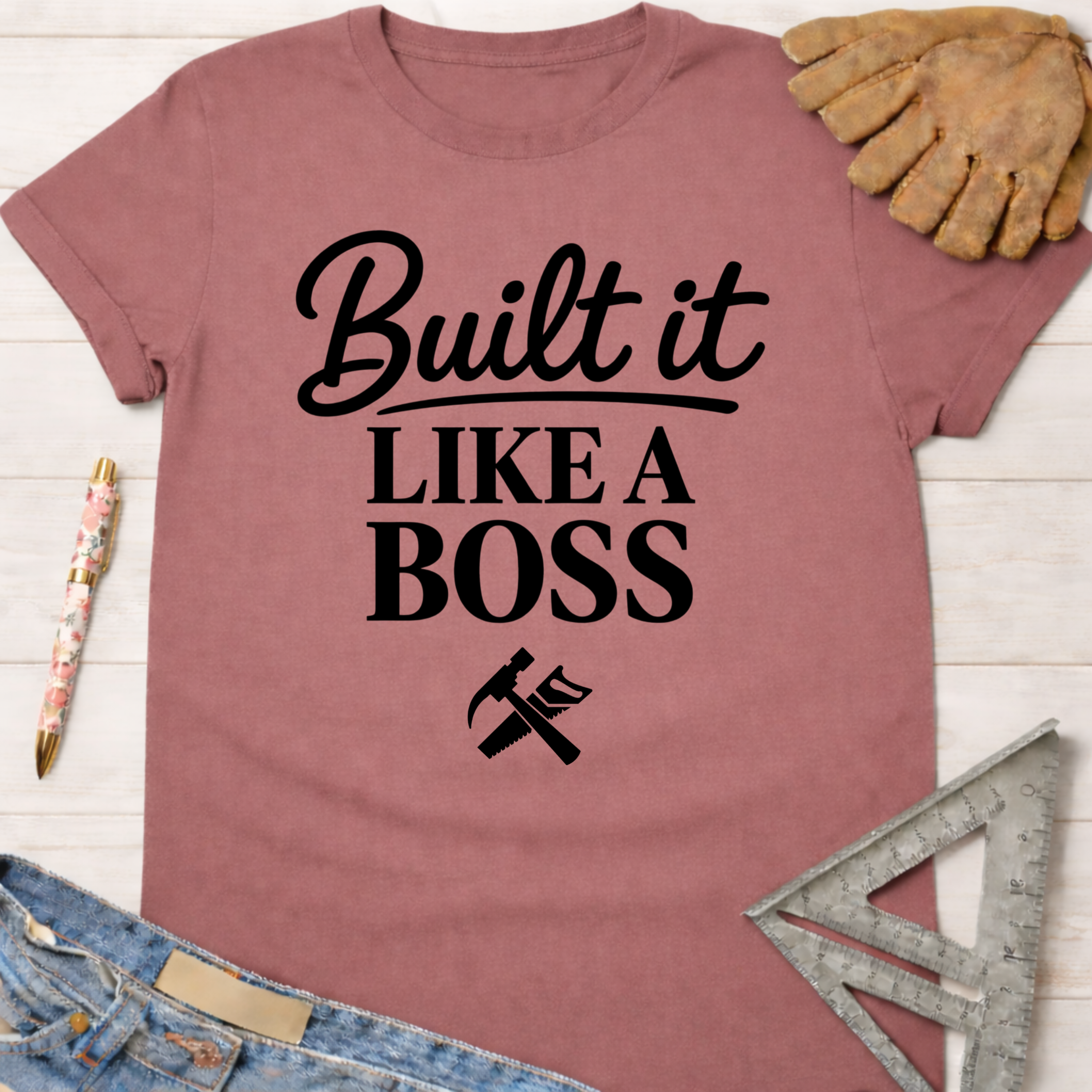 Women's funny woodworking graphic tee shirt for female woodworkers, makers, and DIY builders — Sawdust & Ponytails. Mauve cotton t-shirt with "Built It LIKE A BOSS" text and tools.
