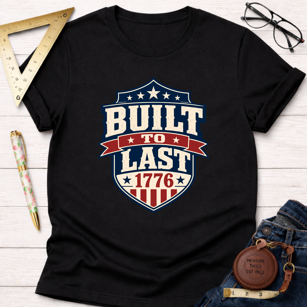 Black cotton t-shirt with a "Built To Last 1776" badge design in red, white, and blue.