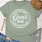 Women's funny woodworking graphic tee shirt for female woodworkers, makers, and DIY builders — Sawdust & Ponytails. Sage green cotton tee with "Built With Grit, Grace, and Wood Filler" graphic.