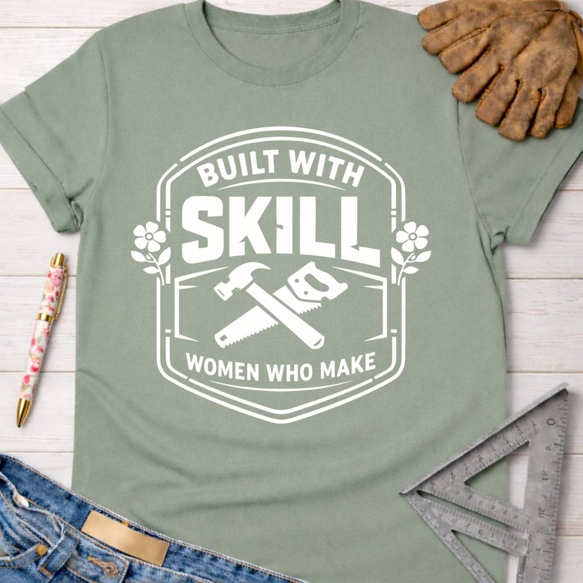 Women's funny woodworking graphic tee shirt for female woodworkers, makers, and DIY builders — Sawdust & Ponytails. Sage green cotton tee with "Built With Skill Women Who Make" graphic, hammer, and saw.