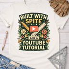 Women's funny woodworking graphic tee shirt for female woodworkers, makers, and DIY builders — Sawdust & Ponytails. White cotton t-shirt with "Built With Spite And A YouTube Tutorial" graphic, featuring a ruler, pencil, and play button surrounded by flowers.