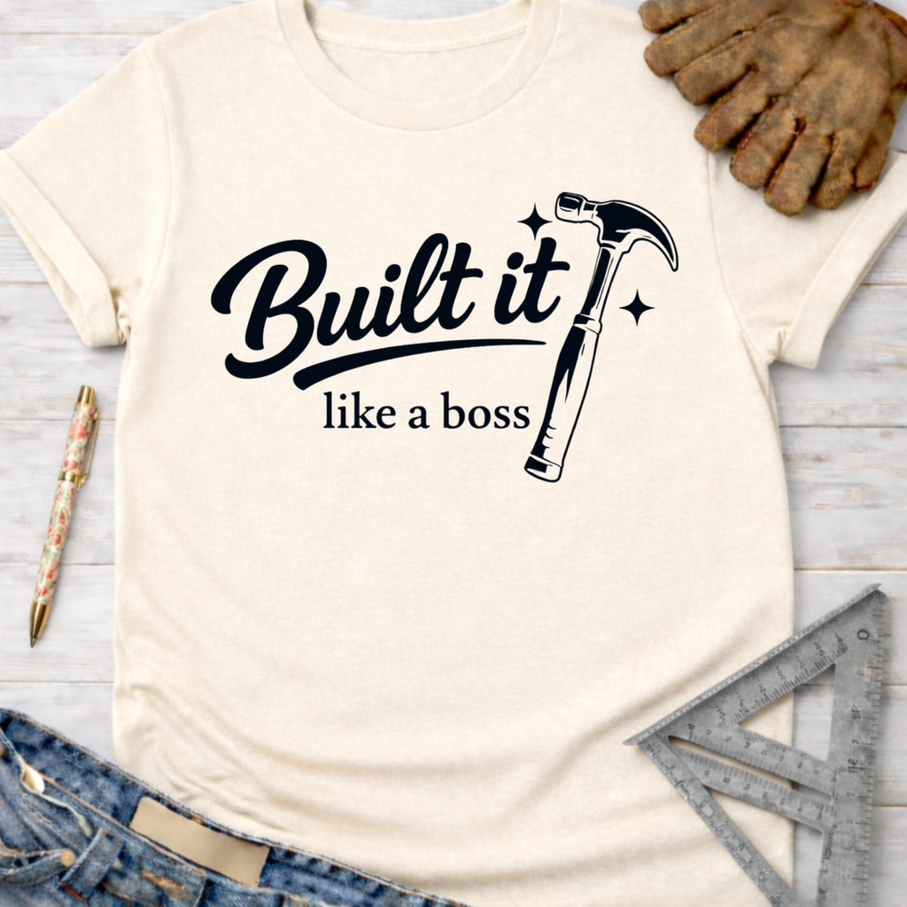 Women's funny woodworking graphic tee shirt for female woodworkers, makers, and DIY builders — Sawdust & Ponytails. Cream "Built it like a boss" t-shirt with hammer graphic.