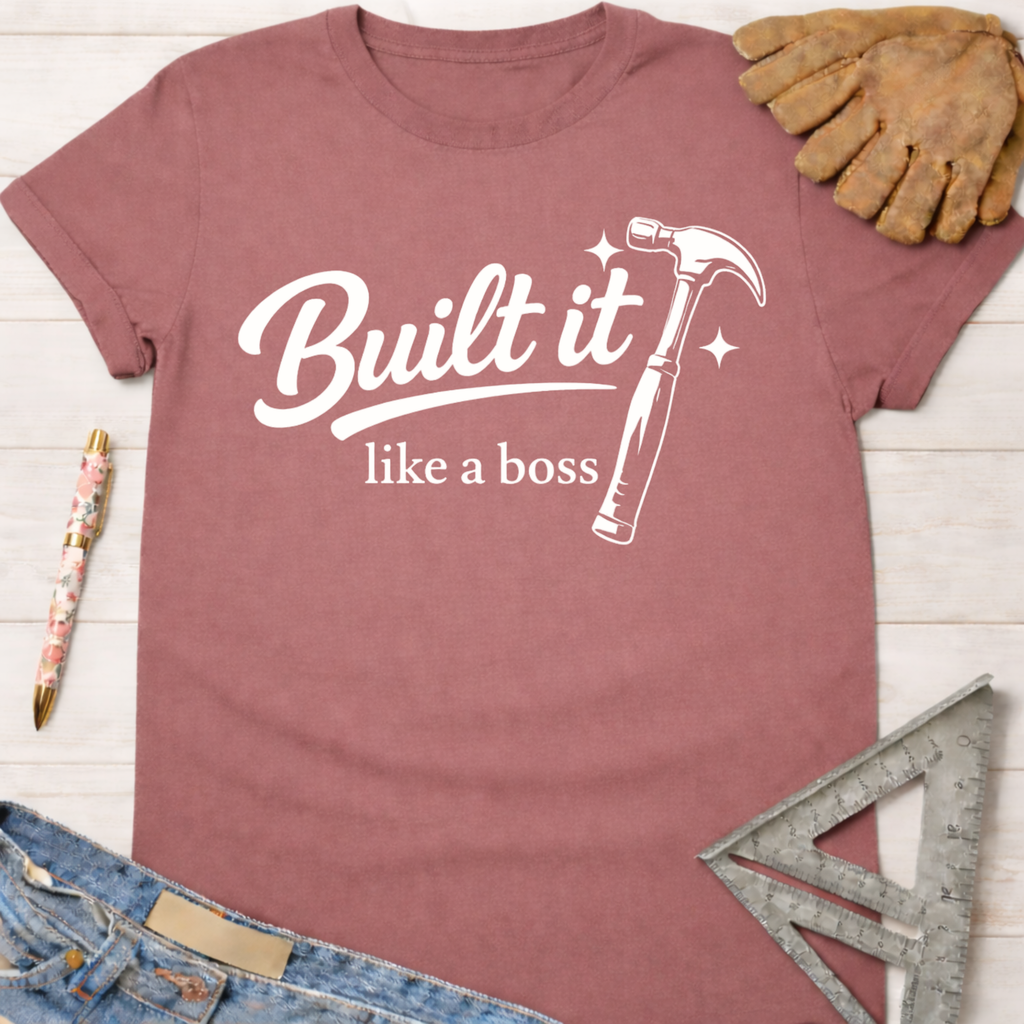 Women's funny woodworking graphic tee shirt for female woodworkers, makers, and DIY builders — Sawdust & Ponytails. Mauve cotton tee with "Built it like a boss" text and hammer graphic.