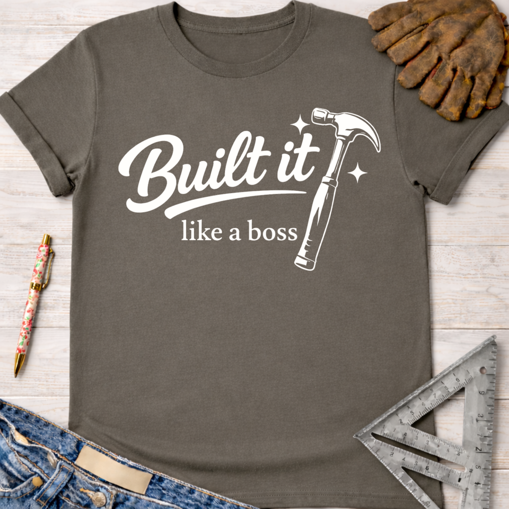 Women's funny woodworking graphic tee shirt for female woodworkers, makers, and DIY builders — Sawdust & Ponytails. Dark gray cotton tee with "Built it like a boss" text and a white hammer graphic.