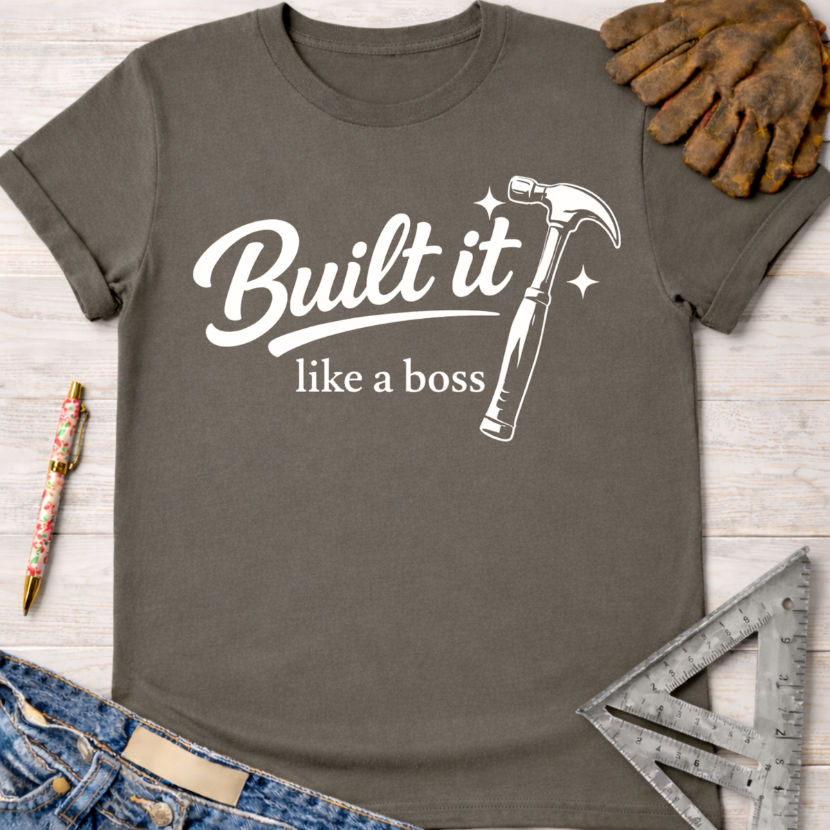 Women's funny woodworking graphic tee shirt for female woodworkers, makers, and DIY builders — Sawdust & Ponytails. Dark gray cotton tee with "Built it like a boss" text and a white hammer graphic.
