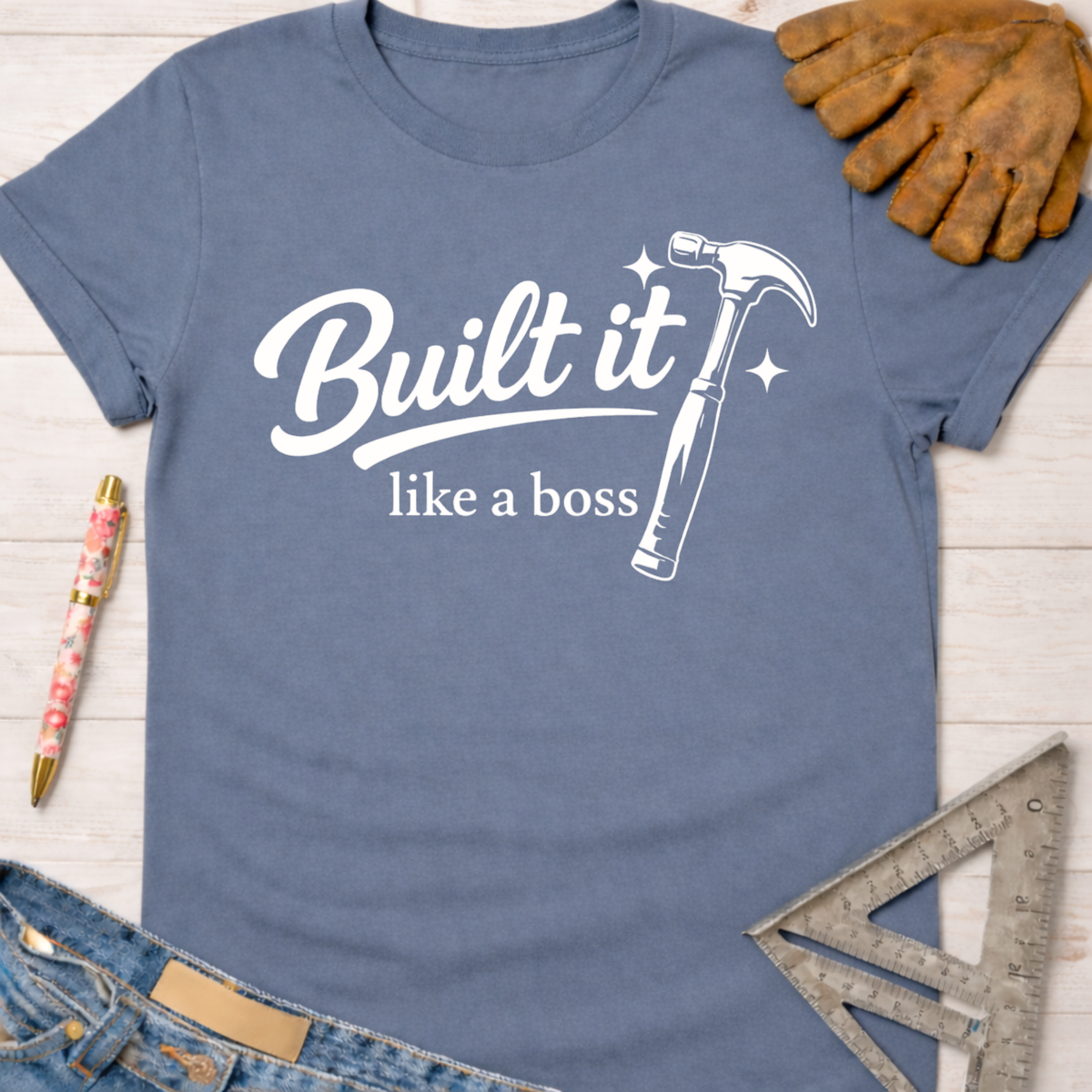 Women's funny woodworking graphic tee shirt for female woodworkers, makers, and DIY builders — Sawdust & Ponytails. Blue cotton tee with "Built it like a boss" text and hammer graphic.