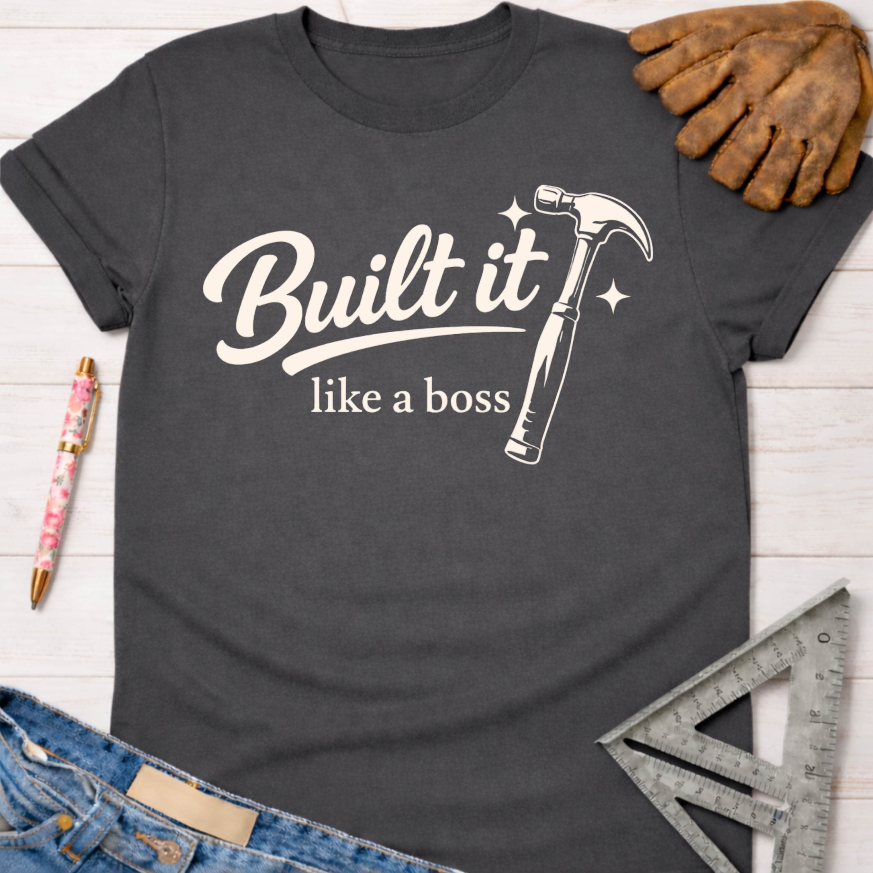 Women's funny woodworking graphic tee shirt for female woodworkers, makers, and DIY builders — Sawdust & Ponytails. Dark gray cotton t-shirt with "Built it like a boss" text and hammer graphic.