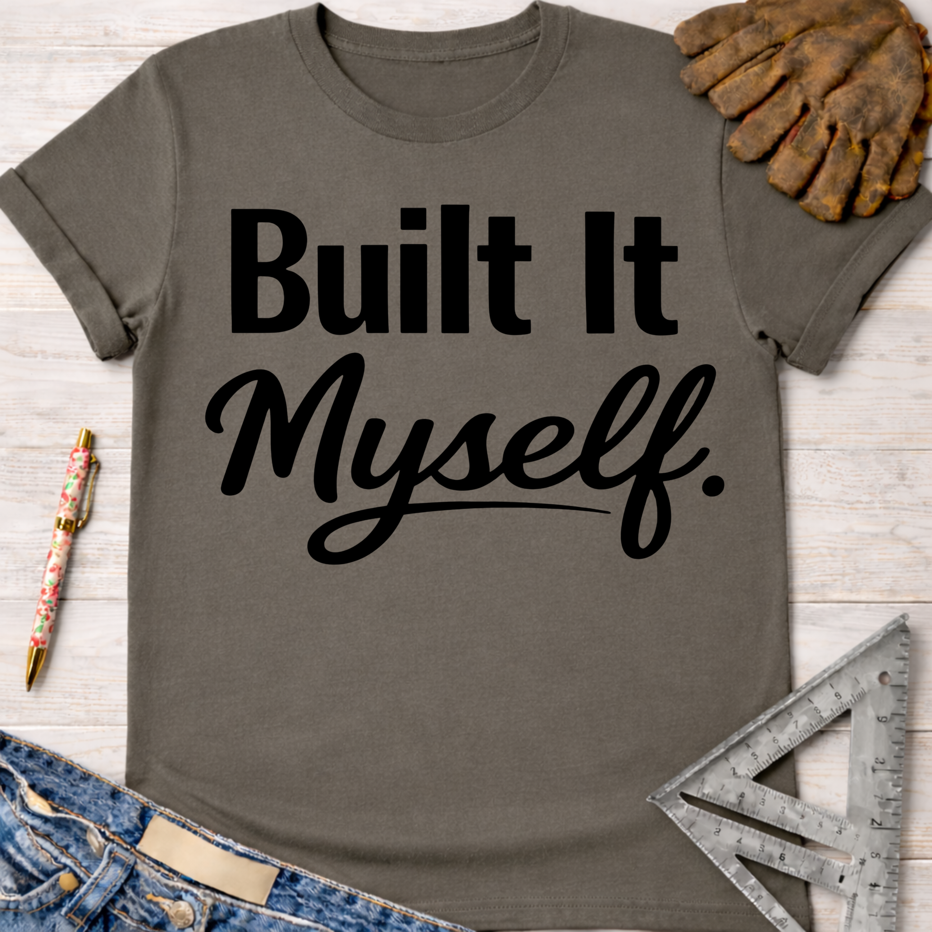 Women's funny woodworking graphic tee shirt for female woodworkers, makers, and DIY builders — Sawdust & Ponytails. Dark gray cotton tee with "Built It Myself" in black text.