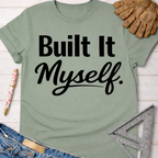 Sage green "Built It Myself" graphic tee for women, with work gloves, jeans, and a ruler. Women's funny woodworking graphic tee shirt for female woodworkers, makers, and DIY builders — Sawdust & Ponytails
