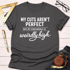 Women's funny woodworking graphic tee shirt for female woodworkers, makers, and DIY builders — Sawdust & Ponytails. Dark gray crewneck t-shirt with "My Cuts Aren't Perfect But My Confidence Is Weirdly High" in white text.