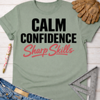 Women's funny woodworking graphic tee shirt for female woodworkers, makers, and DIY builders — Sawdust & Ponytails. Sage green cotton t-shirt with "Calm Confidence Sharp Skills" text.
