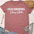 Women's funny woodworking graphic tee shirt for female woodworkers, makers, and DIY builders — Sawdust & Ponytails. Mauve short-sleeve tee with "Calm Confidence. Sharp Skills." in white text.