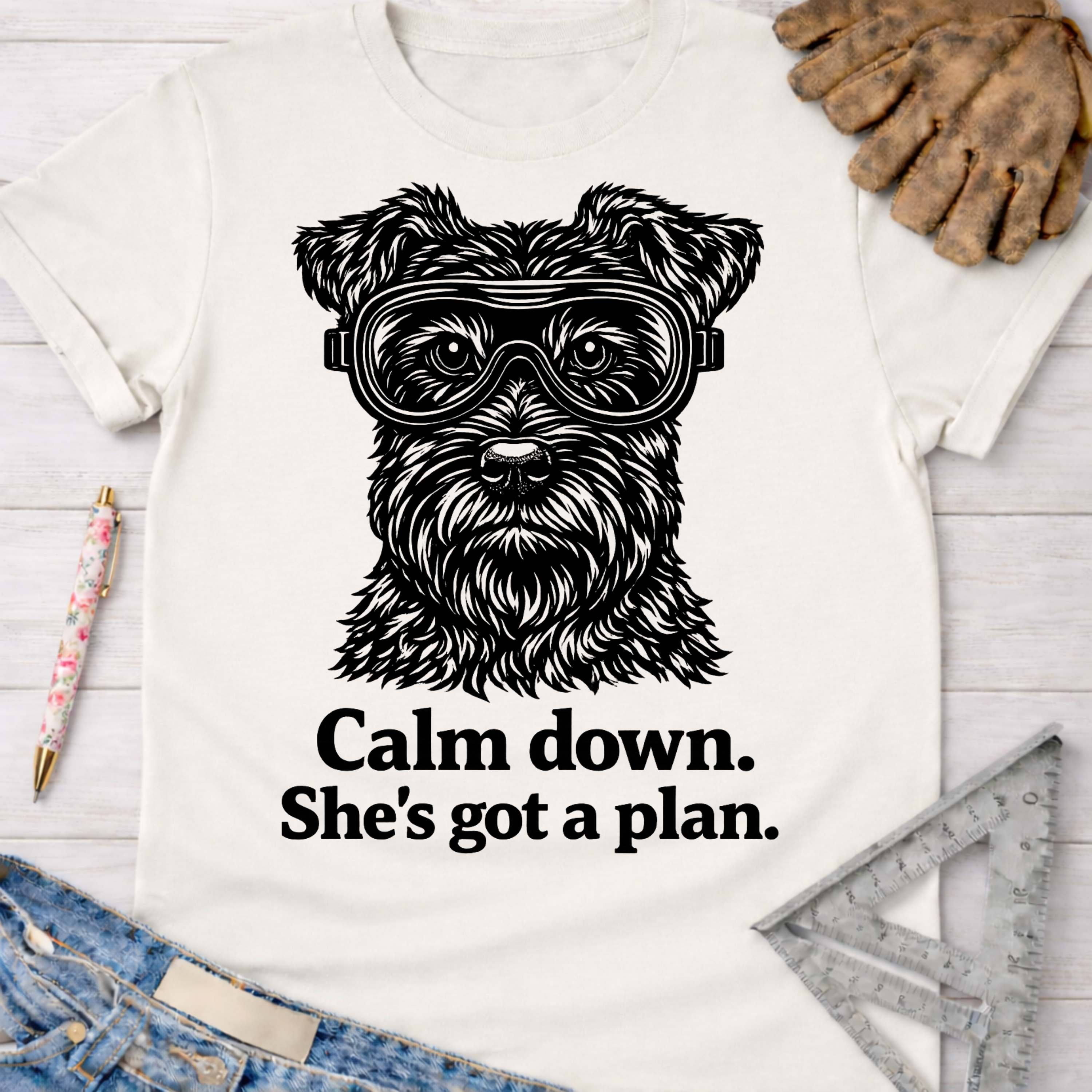 Women's funny woodworking graphic tee shirt for female woodworkers, makers, and DIY builders — Sawdust & Ponytails. White cotton t-shirt with a black schnauzer wearing safety goggles and "Calm down. She's got a plan." text.