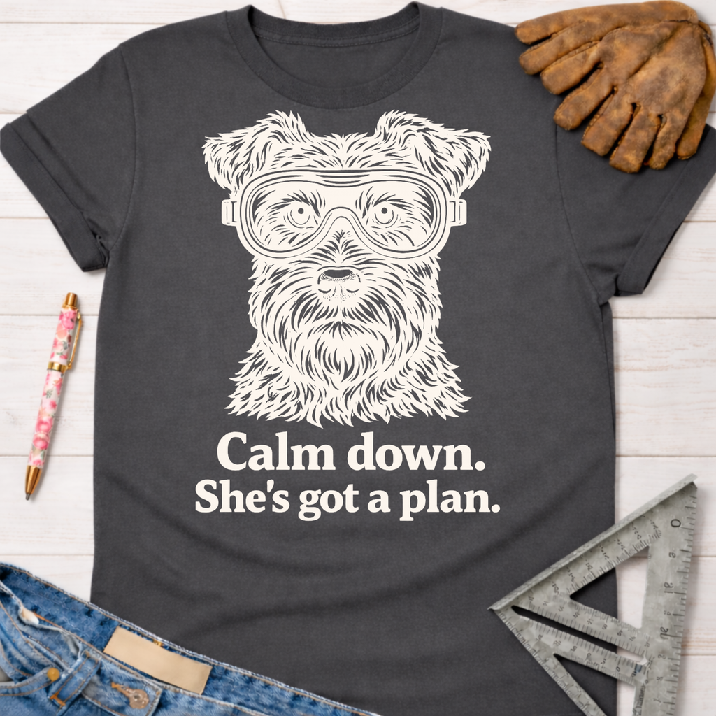 Women's funny woodworking graphic tee shirt for female woodworkers, makers, and DIY builders — Sawdust & Ponytails. Dark gray t-shirt with a white graphic of a dog wearing safety goggles and "Calm down. She's got a plan." text.