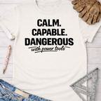 Women's funny woodworking graphic tee shirt for female woodworkers, makers, and DIY builders — Sawdust & Ponytails. White cotton t-shirt with "Calm. Capable. Dangerous with power tools" in black text.