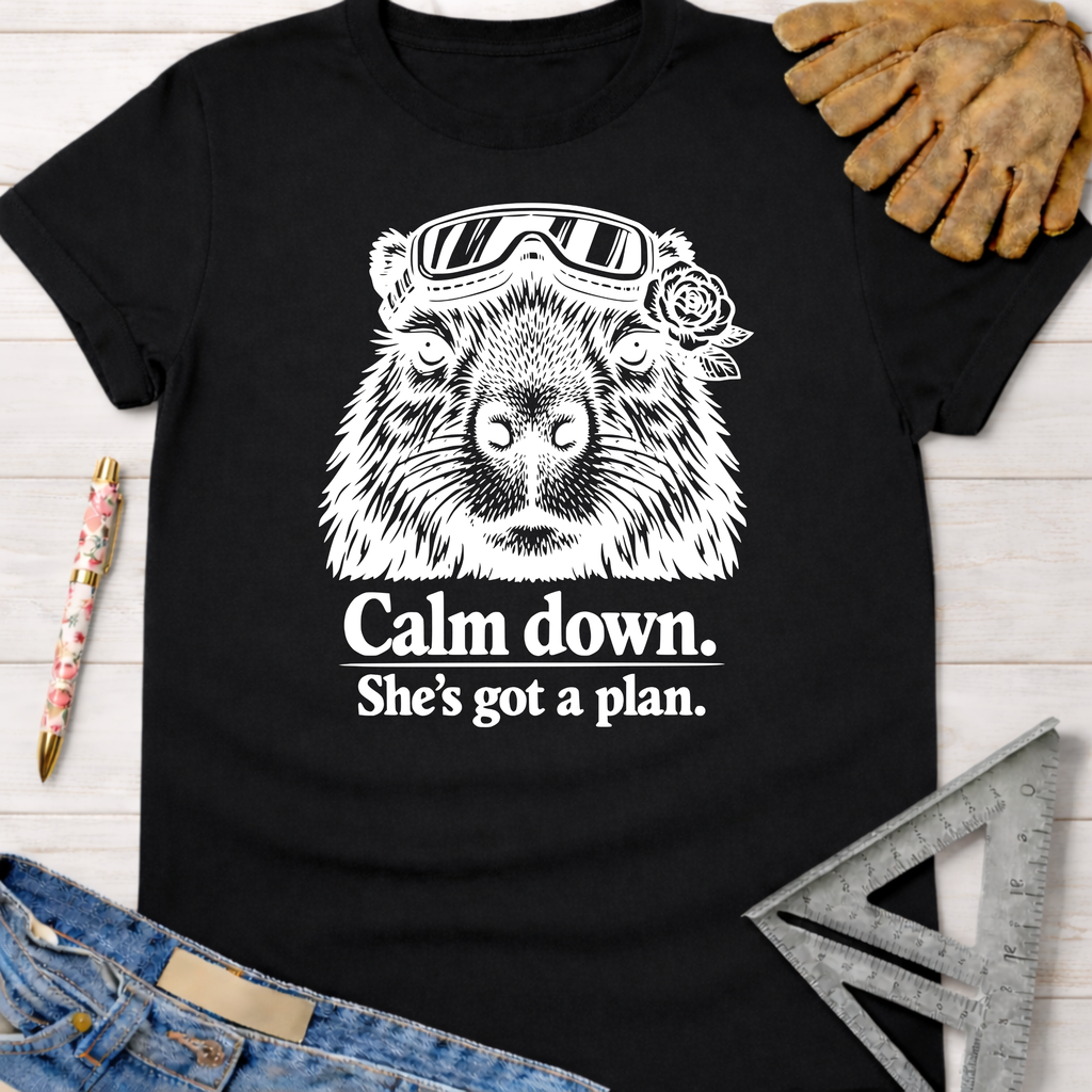 Black women's funny woodworking graphic tee with a capybara in goggles and "Calm down. She's got a plan." text.